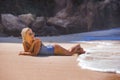 Young sexy and relaxed blond woman in one piece swimsuit lying on the sand looking at sea enjoying summer holidays at beautiful Royalty Free Stock Photo