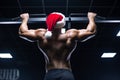 Young sexy Santa Claus in a Christmas hat is working out pumping up back muscles in the gym gaining weight on machines Royalty Free Stock Photo
