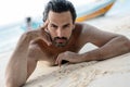 Young sexy stylish handsome latin man lies on a tropical beach, sand on tanned skin, sunbathing vacation concept