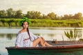 Young woman on boat at sunset. The girl has a flower wreath on her head, relaxing and sailing on river. Fantasy art