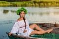 Young woman on boat at sunset. The girl has a flower wreath on her head, relaxing and sailing on river. Fantasy art Royalty Free Stock Photo