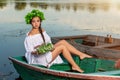 Young woman on boat at sunset. The girl has a flower wreath on her head, relaxing and sailing on river. Fantasy art Royalty Free Stock Photo