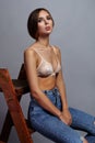 Young woman in bra and jeans sitting on stairs.