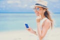 Young woman with earphones using phone on the beach Royalty Free Stock Photo