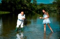 Young sexy woman and old fisherman standing in river with fishing rod. Father and daughter fishing. Mature man fisher Royalty Free Stock Photo