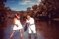 Young sexy woman and old fisherman standing in river with fishing rod. Father and daughter fishing. Mature rich Royalty Free Stock Photo