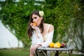 Young sexy woman relaxing and eating orange fruit outdoor. Outdoor fashion photo of beautiful woman with rose in hair Royalty Free Stock Photo