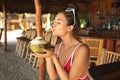 Young and sexy woman sitting in authentic beach bar with a coconut drink Royalty Free Stock Photo