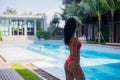 Young woman in swimsuit stand near poolside wearing sunglasses at luxury hotel Royalty Free Stock Photo