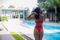 Young woman in swimsuit stand near poolside wearing sunglasses at luxury hotel Royalty Free Stock Photo