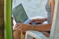 Young sexy woman using laptop on the beach. Girl Freelancer working. Tropical vacation concept. Royalty Free Stock Photo