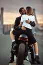 Young sexy woman hugging cute man in stylish black leather jacket, sitting on sports motorcycle on the bridge in the Royalty Free Stock Photo