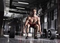 Young shirtless man doing deadlift exercise at gym.