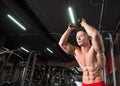 Young shirtless man doing overhead triceps rope extension exercise in modern fitness center. Royalty Free Stock Photo