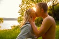 Young Shirtless Man Kissing Girlfriend During Sunset