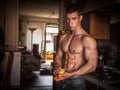 Young shirtless man peeling an apple in kitchen