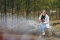 Young shocked beautiful woman sitting on stone studying reading book and clinging to head in city park or forest on Royalty Free Stock Photo