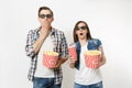 Young shocked couple, woman and man in 3d glasses watching movie film on date, holding bucket of popcorn, cup of soda or Royalty Free Stock Photo