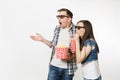 Young shocked couple, woman and man in 3d glasses watching movie film on date, holding bucket of popcorn and plastic cup Royalty Free Stock Photo