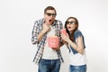 Young shocked couple, woman and man in 3d glasses watching movie film on date, holding bucket of popcorn and plastic cup Royalty Free Stock Photo