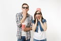 Young shocked couple, woman and man in 3d glasses with bucket for popcorn on head watching movie film on date, holding Royalty Free Stock Photo