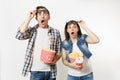 Young shocked couple, woman and man watching movie film on date, holding bucket of popcorn, plastic cup of soda or cola Royalty Free Stock Photo