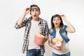 Young shocked couple, woman and man watching movie film on date, holding bucket of popcorn, plastic cup of soda or cola Royalty Free Stock Photo