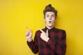 Shocked guy with a funny hairstyle is surprised at a yellow isolated background, hipster with strong hair styling shows at Royalty Free Stock Photo