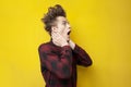 Shocked guy surprised at yellow  background, hipster with funny hairstyle screaming to the side Royalty Free Stock Photo
