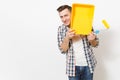 Young shocked handsome man holding paint roller for wall painting and covering face with paint tray isolated on white Royalty Free Stock Photo