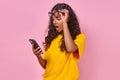 Young shocked Indian woman teen raises glasses and holds phone stands in studio