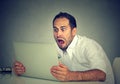 Young shocked man with laptop computer sitting at table