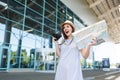 Young shocked traveler tourist woman in hat holding retro vintage photo camera, paper map at international airport