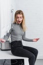 Young shocked woman with smartphone gesturing by hands near broken oven