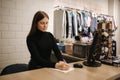 Young shop assistant in clothes store working by comtuper. Beautiful female worker Royalty Free Stock Photo