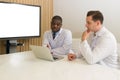 Young short black hair man with moustache and beard dressed in necktie and white gown pointing at laptop computer monitor, present