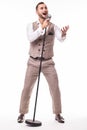 Young showman in suit singing with emotions and pointed gesture over the microphone with energy