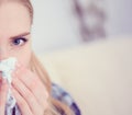 Young sick Caucasian woman sneeze at home on the sofa with a cold. Girl Used tissue paper blowing her nose. Medical and Royalty Free Stock Photo