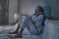 Young sick and depressed black African American woman sitting on bed at home unhappy and sleepless at night feeling overwhelmed Royalty Free Stock Photo