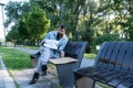 Young sick helpless desperate homeless man sitting on the bench on the urban street in the city holding help paper sign Royalty Free Stock Photo