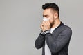 Young sick man having snotty nose, temperature and feeling bad. Sick guy has sneezed, at grey background with