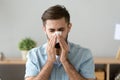 Young sick man holding handkerchief sneezing at work Royalty Free Stock Photo
