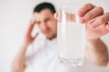 Young sick man isolated over background. Guy hold glass of water with effervescent pills and medicine in it. Suffer from Royalty Free Stock Photo