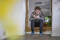 Young sick man with a scarf, blowing his tea in a door frame, holding a thermometer and a cup of tea in his hands Royalty Free Stock Photo