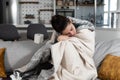 Young sick stressed woman lying at home covered with blanket blowing her nose. Ill female have common cold and flue with runny nos Royalty Free Stock Photo