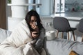 Young sick stressed woman lying at home covered with blanket blowing her nose. Ill female have common cold and flue with runny nos Royalty Free Stock Photo