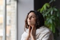 Young sick unhealthy looking woman suffering from sore throat and swollen glands, looking out window Royalty Free Stock Photo