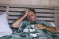 Sick wasted and exhausted man at home bed lying feeling unwell suffering cold and flu sneezing nose with tissues having virus and Royalty Free Stock Photo