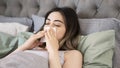 Young sick woman blowing her nose while in bed Royalty Free Stock Photo