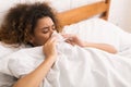 Young sick woman blowing her nose in bed Royalty Free Stock Photo